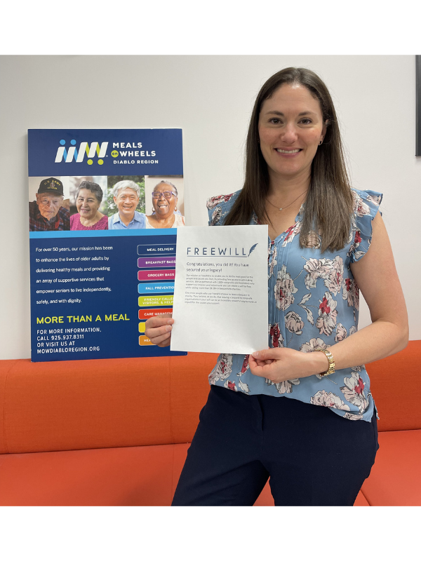 Caitlin Sly smiling and holding up a piece of paper with her completed Will confirmation printed on it.. 