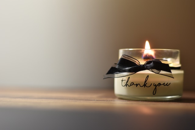 A candle that says thank you. The candle is lit. 