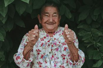 A senior woman giving a thumbs up with a big smile on her face. 