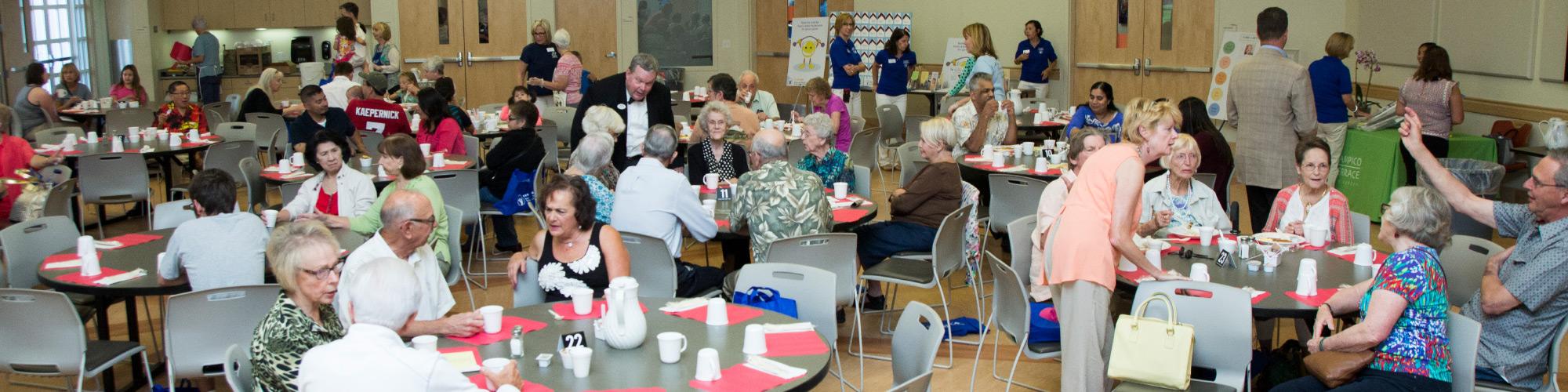 full cafe with seniors eating and talking