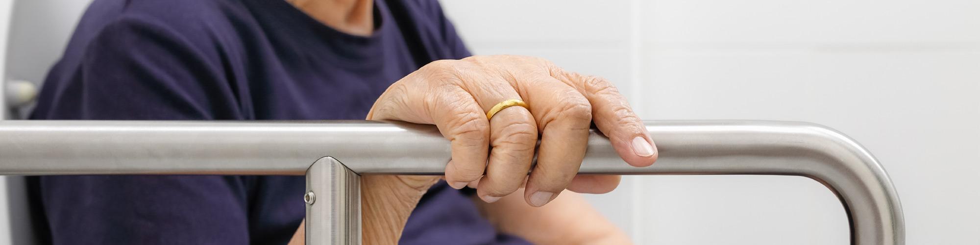 elderly hand holding on a metal handle