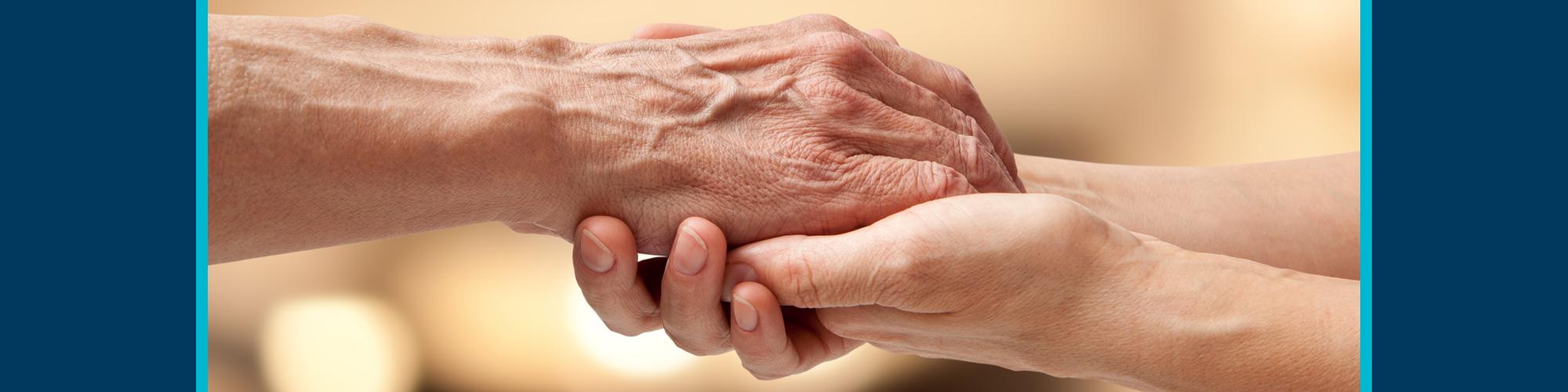 Old hands holding younger person's hands