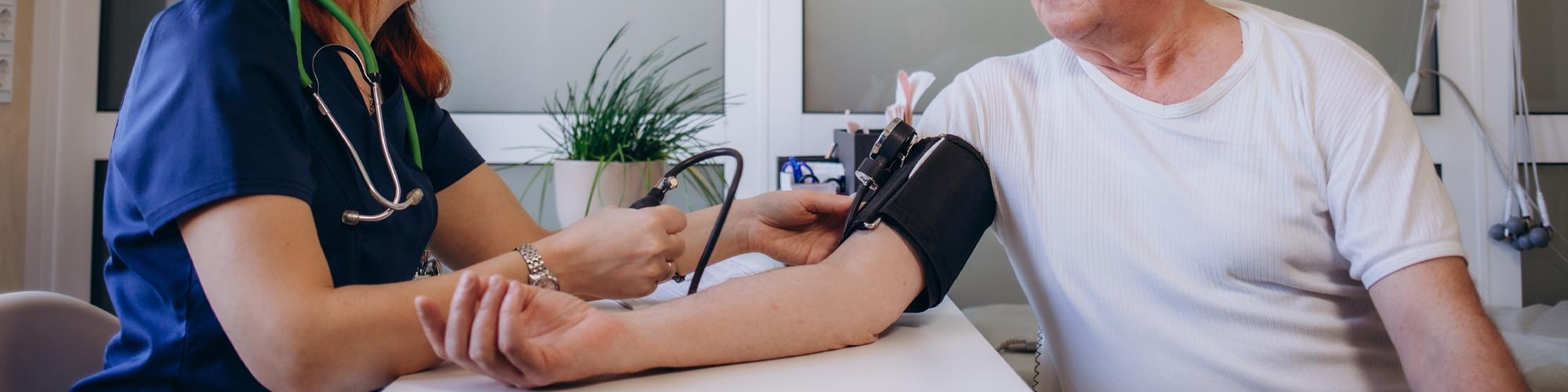 nurse taking the blood pressure of an elderly man
