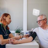 nurse taking the blood pressure of an elderly man