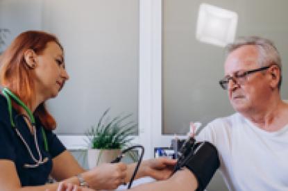 nurse taking the blood pressure of an elderly man
