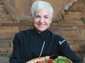 image of a chef smiling holding a basket of vegetables