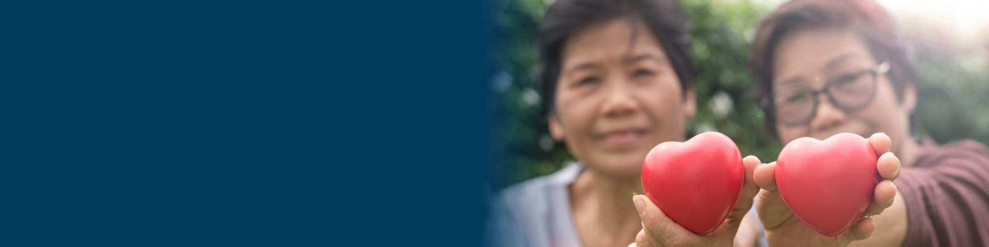 elderly asian twins holding two hearts